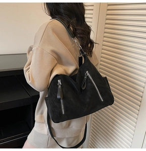 Vue détaillée du grand sac à bandoulière noir avec fermetures éclair argentées et fini mat