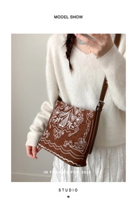 Gros plan d'un sac bandoulière en daim marron avec broderie bohème blanche élégante