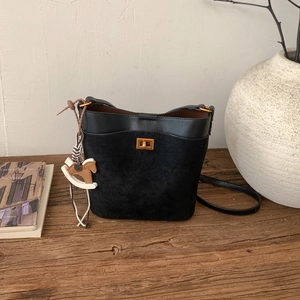 Detail of black leather bucket bag with gold square lock and wooden rocking horse charm