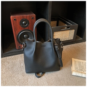 Detail of black lychee grain leather bucket bag with top handles on vintage background