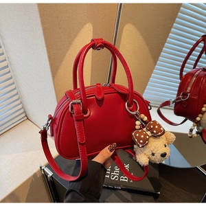 Detailed close-up of a red Boston bag with smooth leather texture and cute bear charm