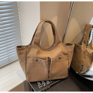 Detail of retro canvas tote bag showing front double pockets and metallic hardware buckles