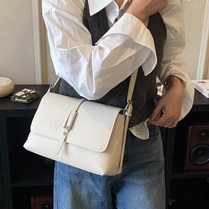 Detail view of the cream-white litchi grain leather texture on a retro square crossbody bag
