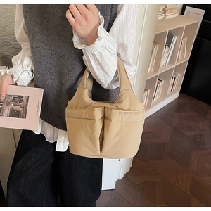 Detail of khaki quilted puffer tote bag with side pockets and wide handles in home setting