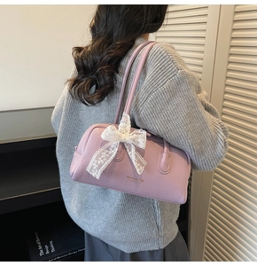 Detail of purple Boston bag with lychee leather texture and lace bow accessory