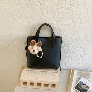 Détail du sac seau noir avec texture litchi et pendentif ours avec nœud à pois