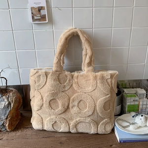 Close-up of beige plush tote bag featuring textured circular embossed patterns and soft fur