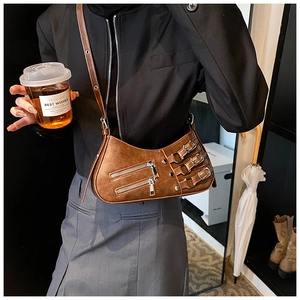 Detail view of retro brown crossbody bag with metal buckles and zippers on a model