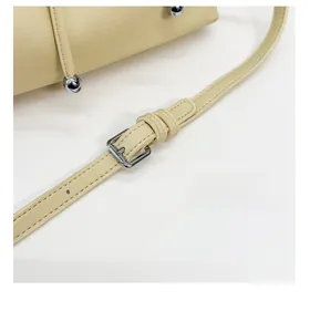 Detail of adjustable cream leather strap with silver metal buckle on a shoulder bag