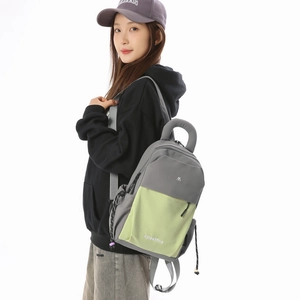 Detail of grey and green lightweight backpack featuring durable nylon fabric and top handle