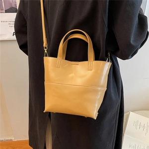 Dettaglio borsa tote in ecopelle gialla con tracolla regolabile e manici su una modella