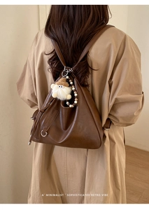Deep brown leather triangle backpack with silver ring hardware and plush doll charm