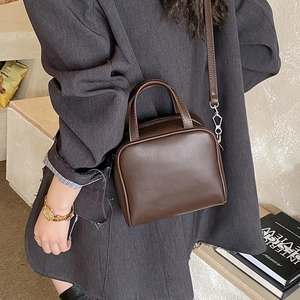 Detailed shot of dark brown PU leather tote bag with silver hardware on a female model