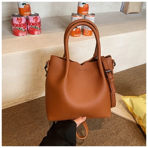 Detailed macro view of brown lychee grain leather handbag with adjustable metal strap buckle