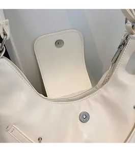 Detail of magnetic silver clasp and zipper closure on beige crescent shoulder bag