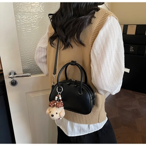 Detailed view of black Boston bag with silver hardware and a cute dog plush pendant charm
