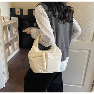 Detail of quilted cream tote bag featuring two front pockets shown in a home setting