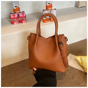 Detail view of brown lychee pattern leather tote bag with sturdy handles and metallic ring