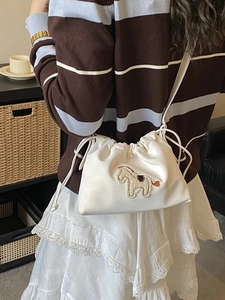 White drawstring bucket crossbody bag with embroidered pony detail shown in a lifestyle setting