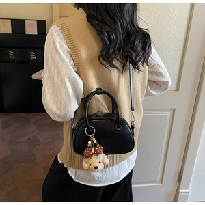 Detailed view of black bowling bag featuring a cute teddy bear plush charm and adjustable strap