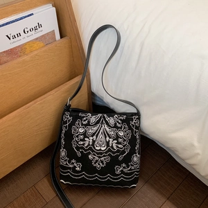 Détail de broderie florale bohème sur sac seau en toile noire avec bandoulière fine