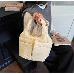 Detailed side view of beige quilted bucket bag with double pockets and soft puffer texture