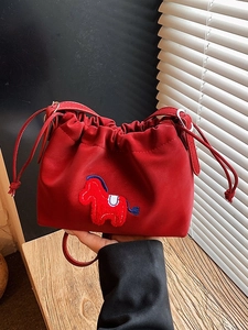 Chic red drawstring bucket bag with horse charm detail and adjustable leather shoulder strap