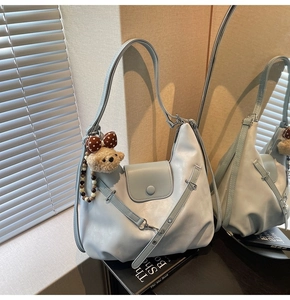 Detailed shot of a silver crescent shoulder bag with a cute plush bear charm accessory