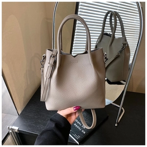 Macro detail of taupe lychee texture leather bucket bag with silver metal buckles