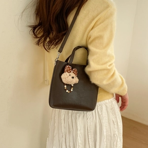 Détail du sac seau marron foncé doté d'un adorable pendentif en forme d'ours en peluche