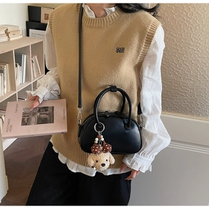 Minimalist black matte leather bowling bag with cute plush dog charm and shoulder strap