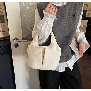 Detail view of cream quilted bucket bag with front patch pockets and soft fabric texture