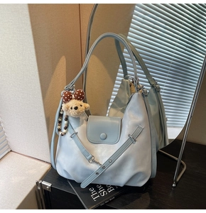 Detail of light blue glossy shoulder bag with cute plush bear and beaded pendant