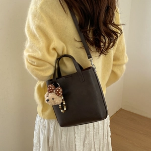 Détail du sac seau en cuir marron foncé avec un charmant ours en peluche et nœud à pois