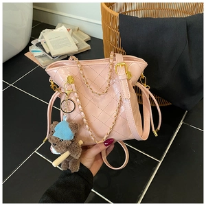 Detail of light pink quilted leather bag with gold chain strap and cute bear charm