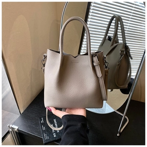 Detailed macro view of taupe lychee grain leather bucket bag with V-shaped top edges
