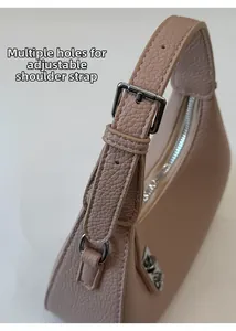 Détail de la bandoulière réglable avec boucle argentée sur un sac en cuir rose nude