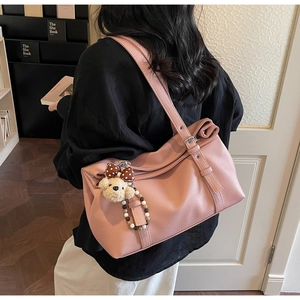 Detail of pink faux leather tote bag featuring a cute teddy bear charm and bow accessory