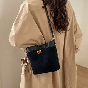 Detail of black bucket bag featuring suede leather textures and a golden swivel lock closure
