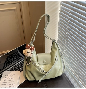 Detail of avocado green hobo bag with teddy bear charm and soft pleated texture