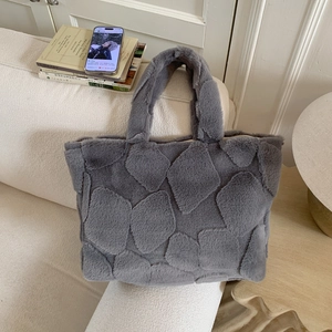 Detail view of grey plush tote bag with geometric texture on a cozy home sofa