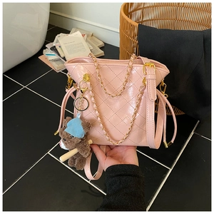 Detailed macro view of pink quilted bucket bag with gold chain and plush bear charm