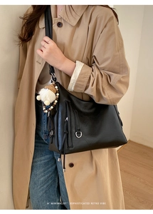 Detail of minimalist black PU leather hobo bag with cute doll pendant and tassel