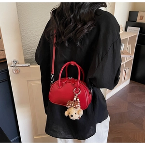 Detail of red bowling bag with plush dog charm and adjustable shoulder strap style