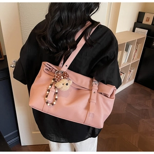Detail view of pink lychee-textured tote bag with decorative buckle and cute bear charm