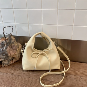 Detailed shot of cream leather dumpling bag with decorative bow and silver hardware