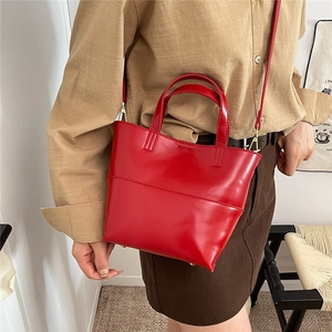 Primo piano di una mini borsa tote rossa lucida abbinata a una camicia color kaki