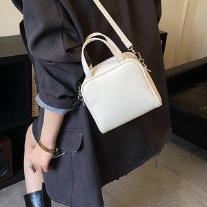 Minimalist cream white square tote bag styled with a dark blazer for a chic look
