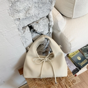 Detailed macro view of cream leather handbag with elegant bow and silver metal bead accents
