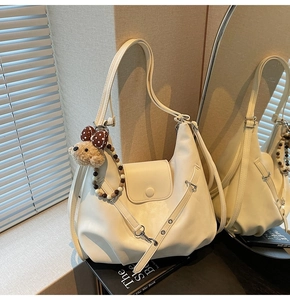 Detail of off-white PU leather hobo bag with teddy bear charm and polka dot bow accessory